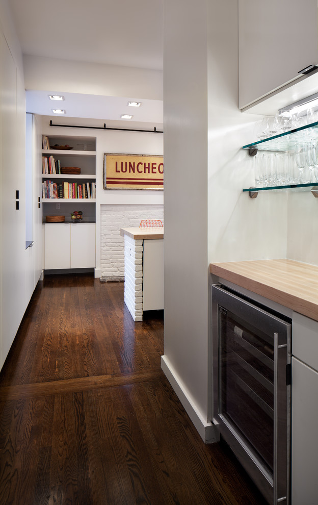 Modelo de cocina comedor moderna con fregadero bajoencimera, armarios con paneles lisos, puertas de armario blancas, encimera de madera y electrodomésticos de acero inoxidable