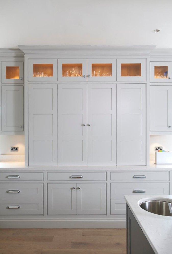 Modelo de cocina clásica con fregadero de doble seno, armarios con rebordes decorativos, puertas de armario grises y encimera de cuarzo compacto