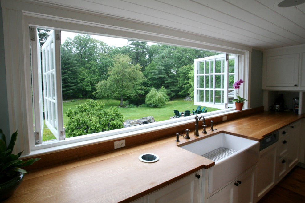 Exemple d'une cuisine américaine nature avec un évier posé, un placard à porte plane, des portes de placard blanches, un plan de travail en bois et parquet foncé.