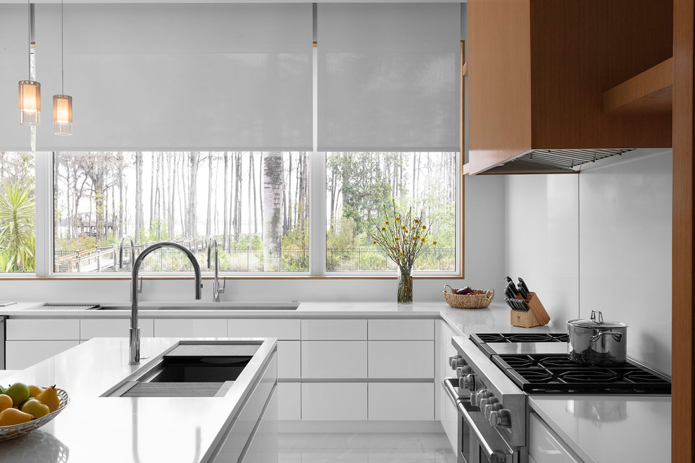 Ejemplo de cocina moderna grande con armarios tipo vitrina, salpicadero blanco, electrodomésticos de acero inoxidable y una isla