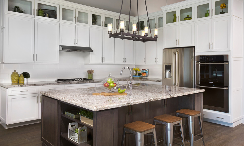 Inspiration for a mid-sized transitional l-shaped dark wood floor kitchen remodel in Phoenix with shaker cabinets, white cabinets, granite countertops, white backsplash, subway tile backsplash, stainless steel appliances, an island and an undermount sink