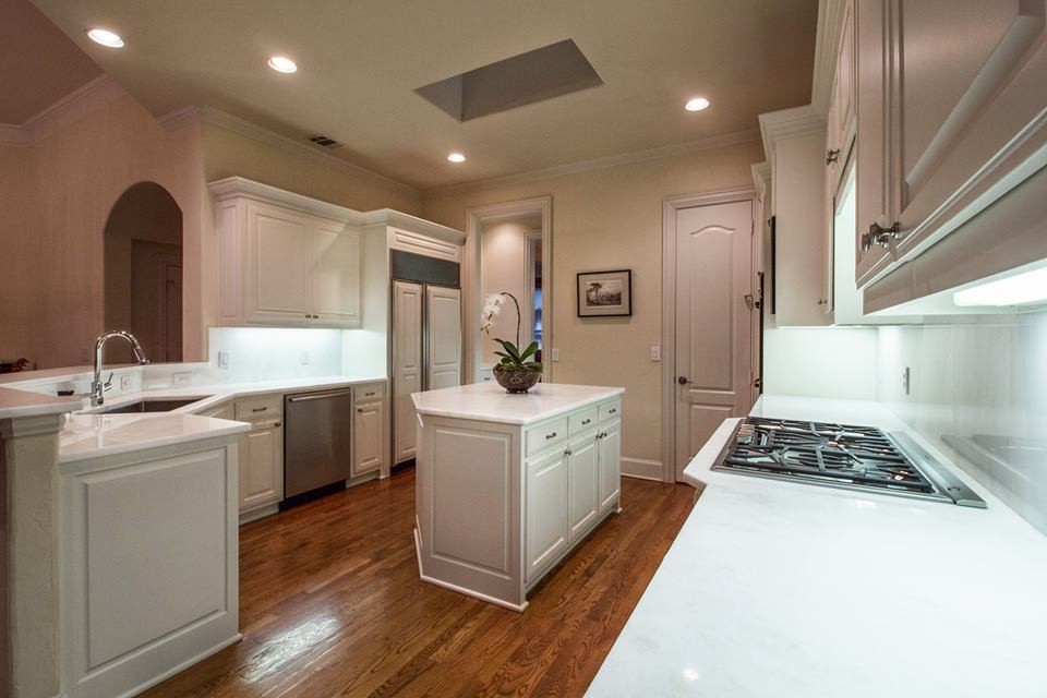 Example of a transitional medium tone wood floor kitchen design in Dallas with shaker cabinets, white cabinets, marble countertops, white backsplash, marble backsplash and an island