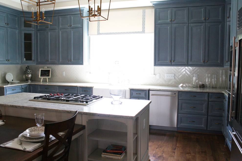 Klassisk inredning av ett kök, med en rustik diskho, luckor med upphöjd panel, blå skåp, granitbänkskiva, gult stänkskydd, stänkskydd i tunnelbanekakel, rostfria vitvaror, mellanmörkt trägolv och en köksö