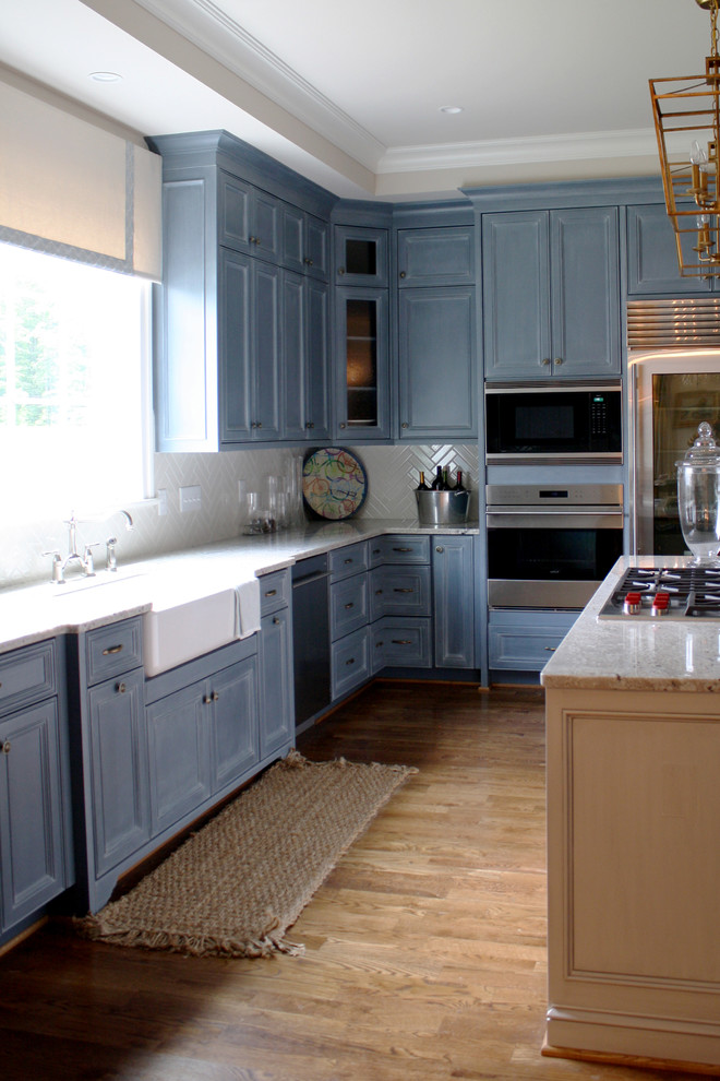Inspiration for a transitional u-shaped medium tone wood floor open concept kitchen remodel in Richmond with a farmhouse sink, raised-panel cabinets, blue cabinets, granite countertops, yellow backsplash, subway tile backsplash, stainless steel appliances and an island