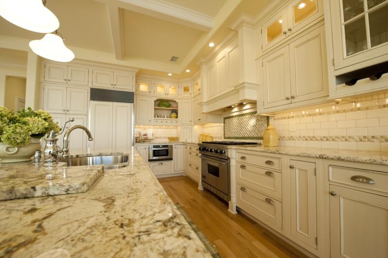 Enclosed kitchen - mid-sized traditional galley medium tone wood floor enclosed kitchen idea in New York with a double-bowl sink, recessed-panel cabinets, white cabinets, granite countertops, beige backsplash, ceramic backsplash, paneled appliances and an island