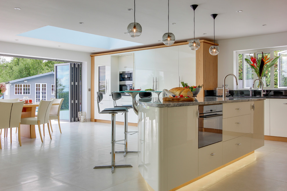 Moderne Wohnküche mit Unterbauwaschbecken, flächenbündigen Schrankfronten, weißen Schränken, Küchengeräten aus Edelstahl, Kücheninsel und Porzellan-Bodenfliesen in Hertfordshire