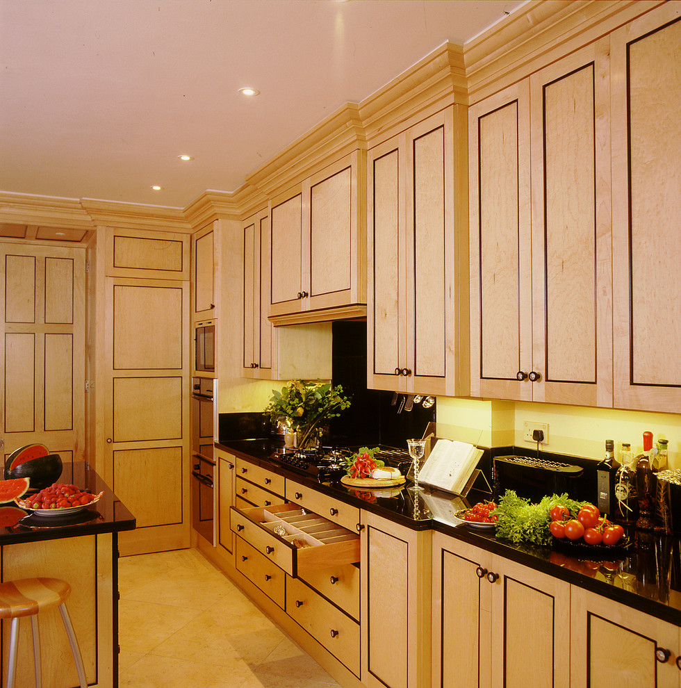 Foto di una grande cucina chic con elettrodomestici neri, lavello a doppia vasca, ante a filo, ante in legno chiaro, top in granito, pavimento in pietra calcarea, pavimento beige e top nero