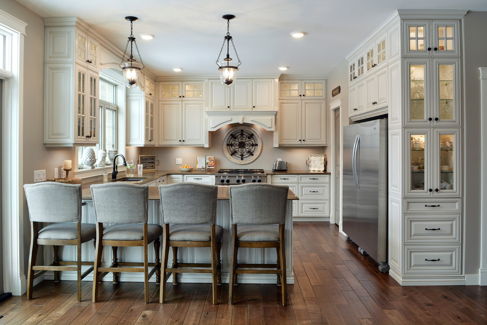 Inspiration for a timeless u-shaped dark wood floor and brown floor kitchen remodel in Other with an undermount sink, raised-panel cabinets, beige cabinets, gray backsplash, stainless steel appliances, a peninsula and black countertops