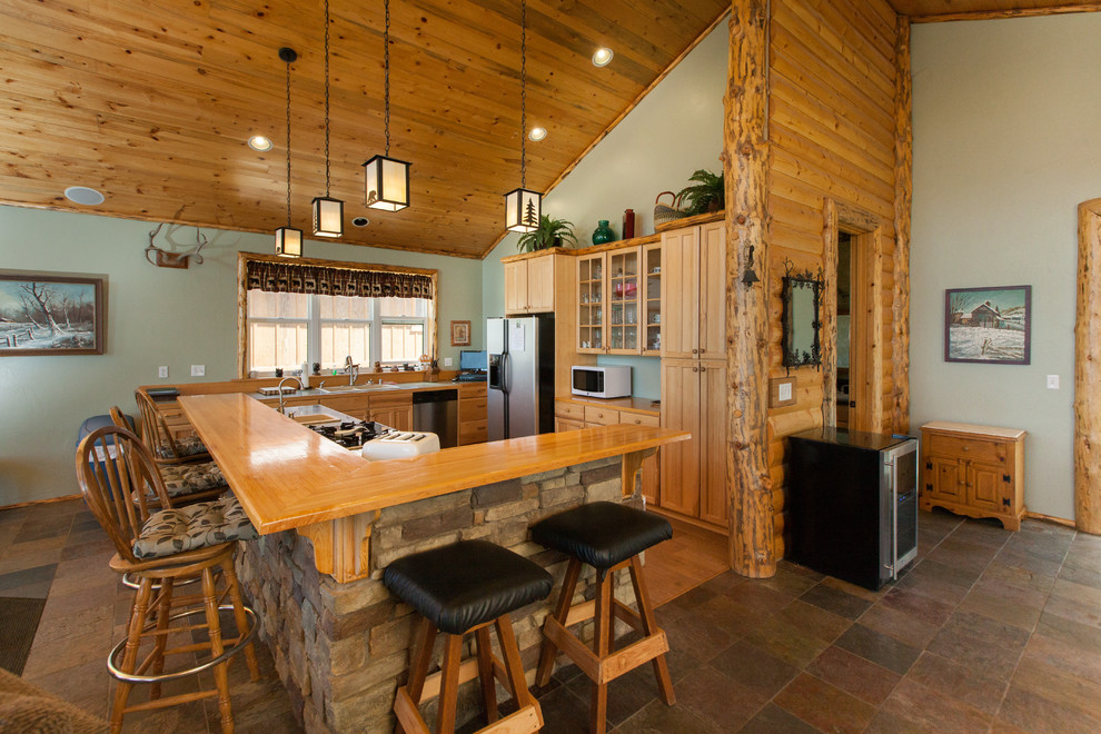This is an example of a rustic u-shaped kitchen in Los Angeles with medium wood cabinets, stainless steel appliances, an island and brown floors.