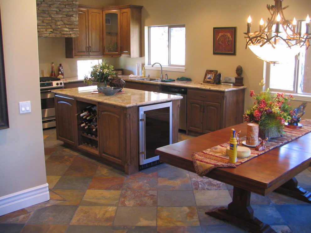 Inredning av ett rustikt mellanstort u-kök, med en undermonterad diskho, luckor med upphöjd panel, skåp i slitet trä, granitbänkskiva, rostfria vitvaror, skiffergolv och en köksö