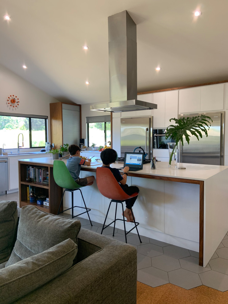 Mid-sized 1960s l-shaped porcelain tile, gray floor and vaulted ceiling open concept kitchen photo in San Diego with an undermount sink, flat-panel cabinets, white cabinets, quartz countertops, white backsplash, quartz backsplash, stainless steel appliances, an island and white countertops