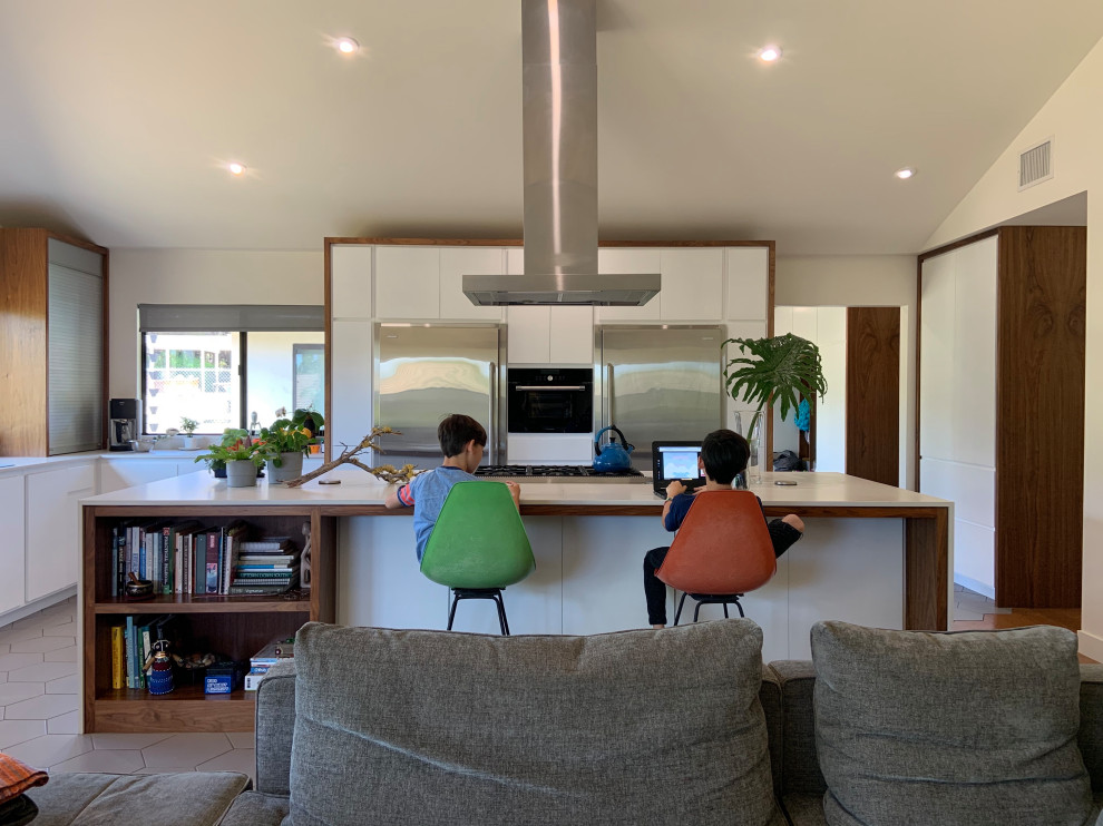 Mid-sized 1950s l-shaped porcelain tile, gray floor and vaulted ceiling open concept kitchen photo in San Diego with an undermount sink, flat-panel cabinets, white cabinets, quartz countertops, white backsplash, quartz backsplash, stainless steel appliances, an island and white countertops