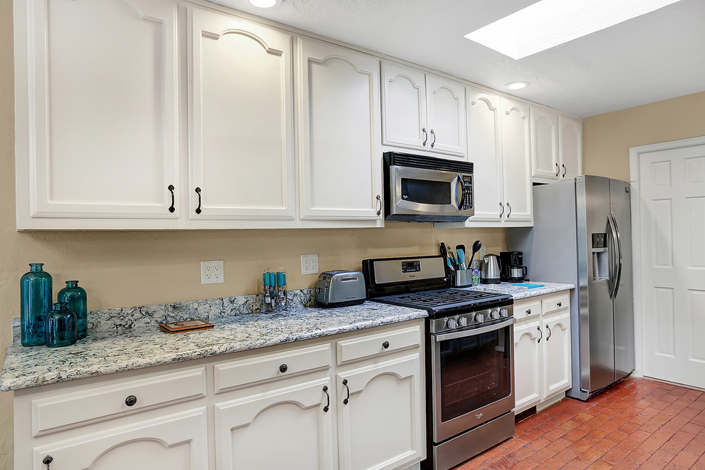 Exempel på ett mellanstort klassiskt kök, med en undermonterad diskho, luckor med infälld panel, turkosa skåp, bänkskiva i kvarts, rostfria vitvaror, tegelgolv och en köksö