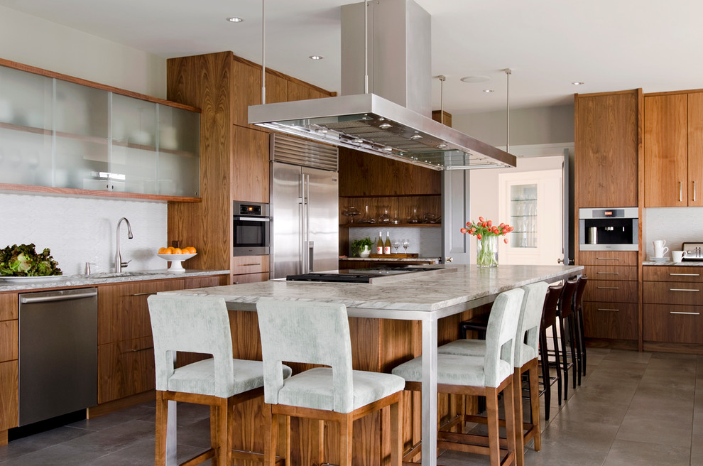 Immagine di un cucina con isola centrale moderno con lavello sottopiano, ante lisce, ante in legno scuro, paraspruzzi bianco e elettrodomestici in acciaio inossidabile