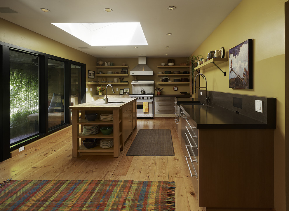 Bild på ett mellanstort, avskilt funkis l-kök, med rostfria vitvaror, skåp i rostfritt stål, öppna hyllor, en rustik diskho, ljust trägolv, en köksö och bänkskiva i koppar