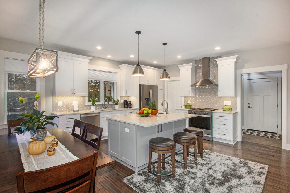Example of a large transitional l-shaped medium tone wood floor and brown floor eat-in kitchen design in Grand Rapids with an undermount sink, shaker cabinets, white cabinets, gray backsplash, stainless steel appliances, an island, white countertops, quartzite countertops and ceramic backsplash