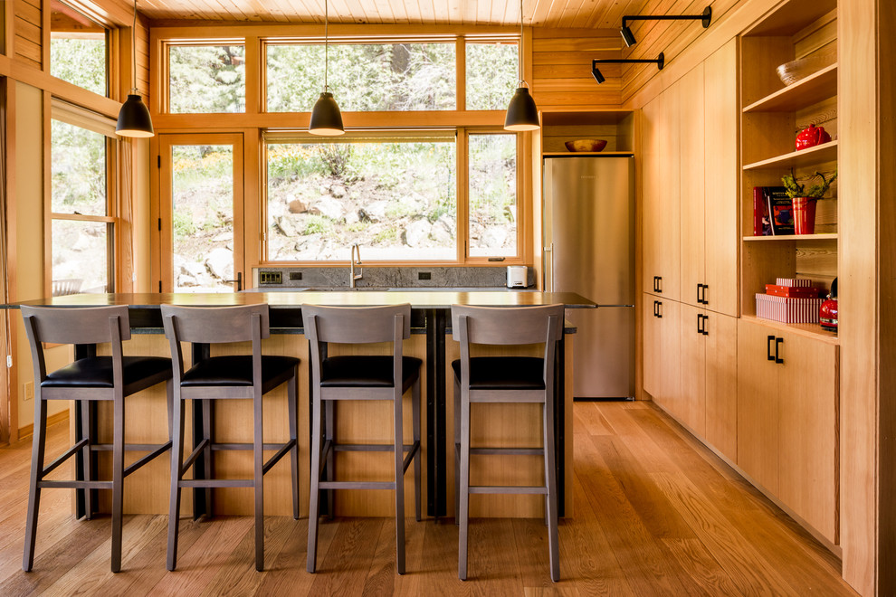 This is an example of a medium sized rustic l-shaped open plan kitchen in Seattle with a single-bowl sink, flat-panel cabinets, medium wood cabinets, stainless steel appliances, medium hardwood flooring and an island.