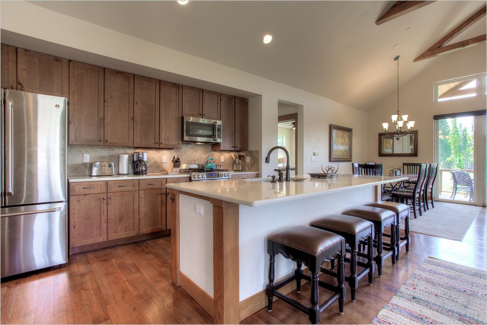This is an example of a large classic open plan kitchen in Denver with a double-bowl sink, medium wood cabinets, composite countertops, stainless steel appliances, medium hardwood flooring and an island.