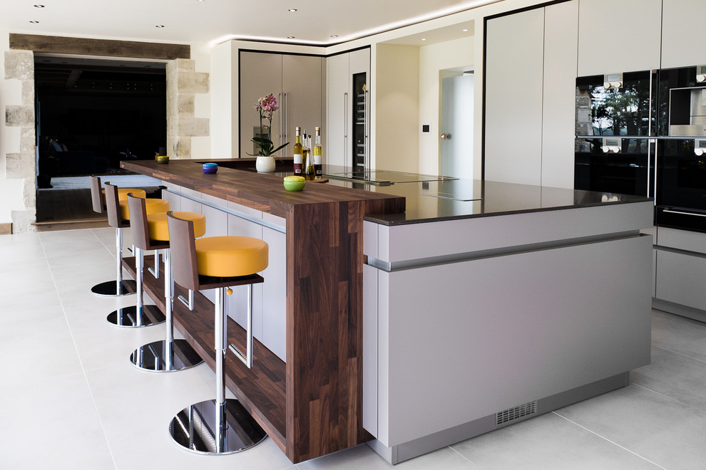 Idée de décoration pour une grande cuisine parallèle design avec un placard à porte plane, des portes de placard grises, un électroménager en acier inoxydable, sol en béton ciré et îlot.