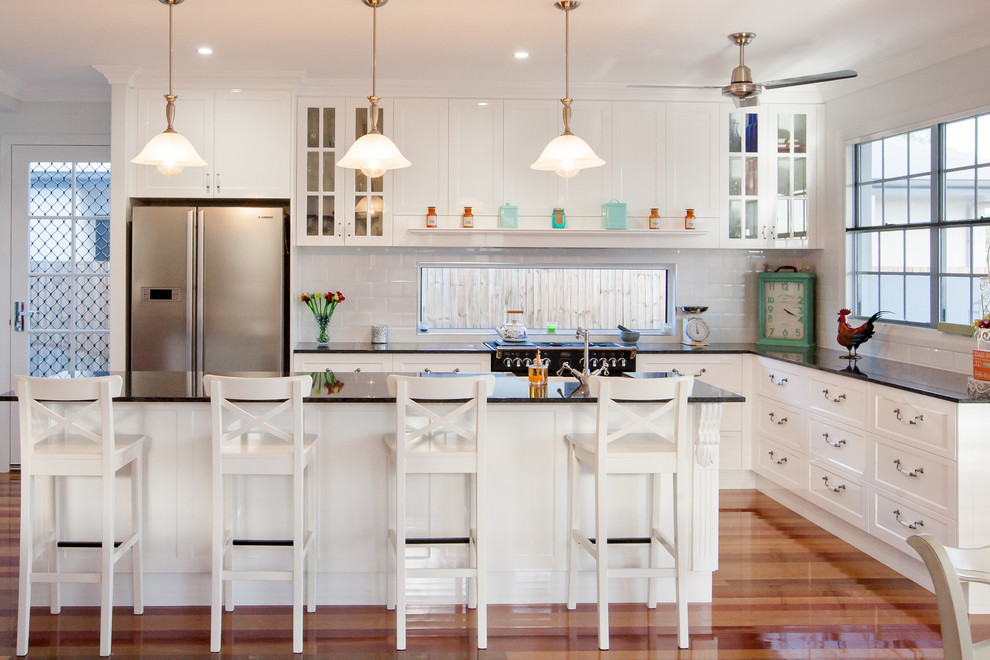 Exempel på ett lantligt kök, med en rustik diskho, luckor med infälld panel, vita skåp, vitt stänkskydd, rostfria vitvaror och en köksö