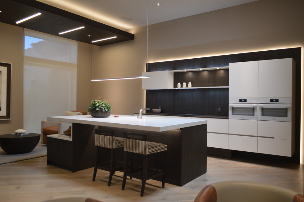Bild på ett mellanstort funkis kök och matrum, med en integrerad diskho, släta luckor, vita skåp, bänkskiva i kvarts, brunt stänkskydd, ljust trägolv och en köksö