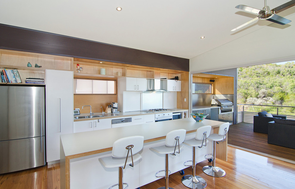 This is an example of a coastal single-wall kitchen in Perth with a double-bowl sink, flat-panel cabinets, white cabinets, light hardwood flooring and an island.