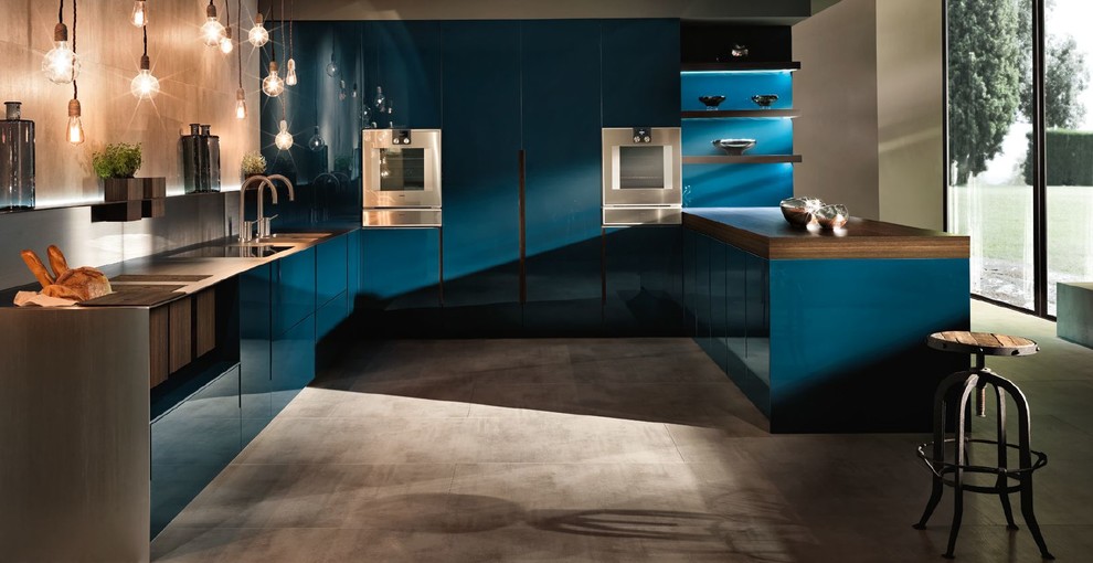 Example of a huge trendy u-shaped concrete floor and gray floor kitchen pantry design in San Francisco with an integrated sink, flat-panel cabinets, blue cabinets, stainless steel countertops, gray backsplash, stainless steel appliances, a peninsula and gray countertops