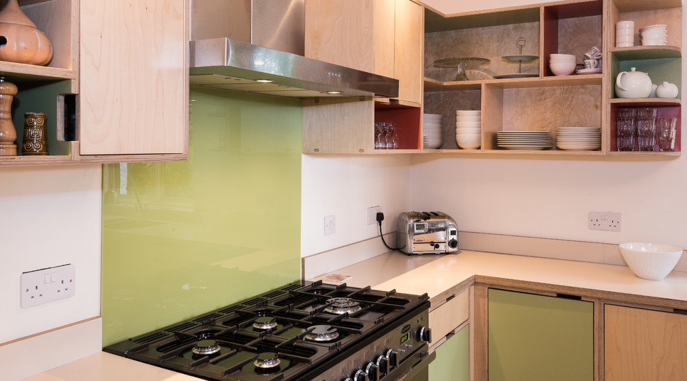 Immagine di una cucina minimalista di medie dimensioni con lavello a doppia vasca, ante in legno chiaro, top in legno, paraspruzzi verde, paraspruzzi con lastra di vetro e elettrodomestici in acciaio inossidabile