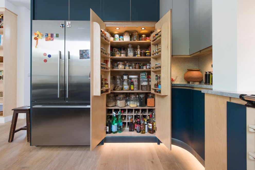 Große Moderne Küche mit flächenbündigen Schrankfronten, blauen Schränken, Granit-Arbeitsplatte, Küchenrückwand in Beige und hellem Holzboden in Cornwall