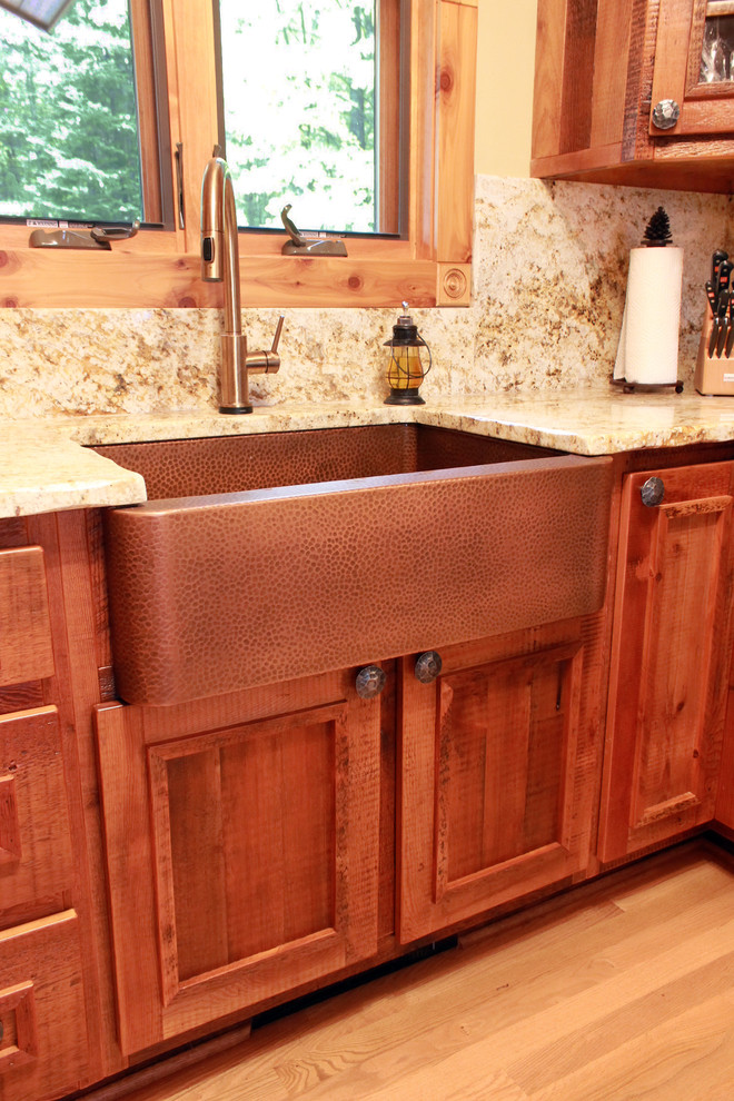 Foto på ett litet rustikt kök, med en rustik diskho, luckor med upphöjd panel, skåp i slitet trä, granitbänkskiva, flerfärgad stänkskydd, stänkskydd i sten, rostfria vitvaror och mellanmörkt trägolv