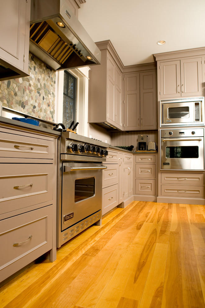 Inredning av ett klassiskt kök, med skåp i shakerstil, bruna skåp, beige stänkskydd, stänkskydd i trä, rostfria vitvaror, mellanmörkt trägolv och brunt golv