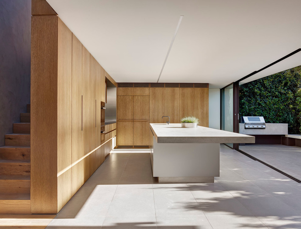 Large modern l-shaped open plan kitchen in Sydney with an integrated sink, flat-panel cabinets, medium wood cabinets, concrete worktops, metallic splashback, metal splashback, black appliances, ceramic flooring and an island.