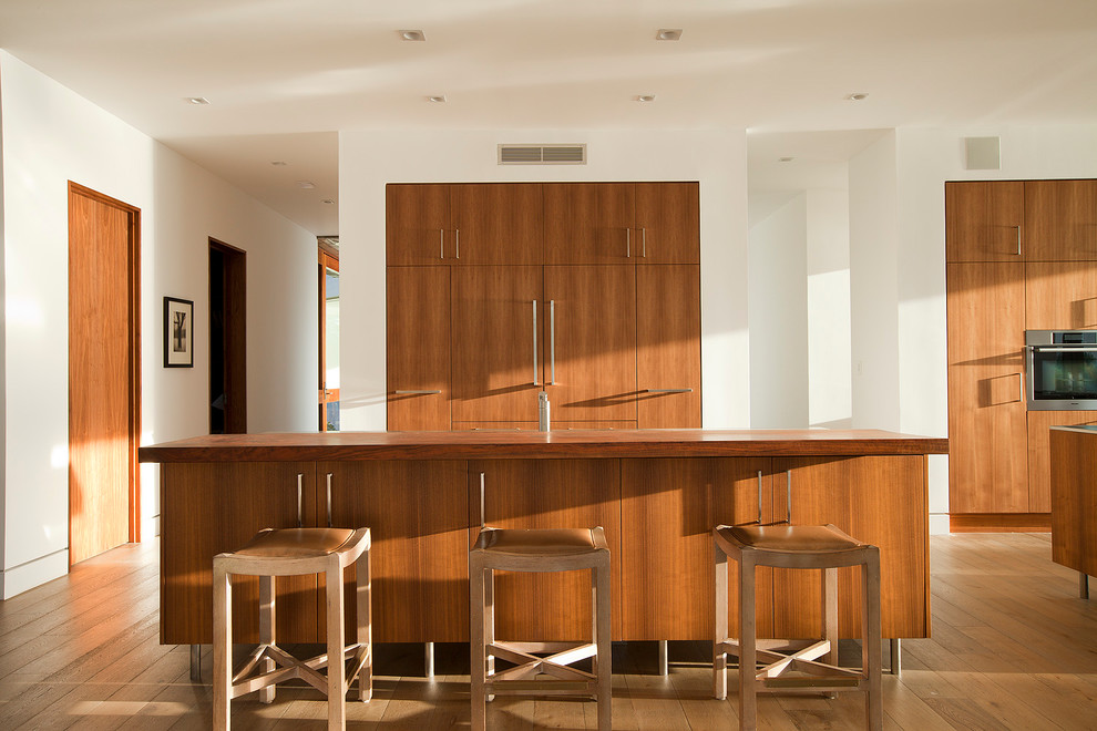 Esempio di un cucina con isola centrale costiero con ante lisce, ante in legno scuro, top in legno e pavimento in legno massello medio