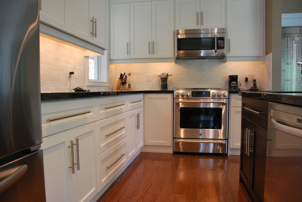Example of a mid-sized trendy l-shaped dark wood floor open concept kitchen design in Toronto with a double-bowl sink, shaker cabinets, white cabinets, solid surface countertops, white backsplash, stone tile backsplash, stainless steel appliances and an island