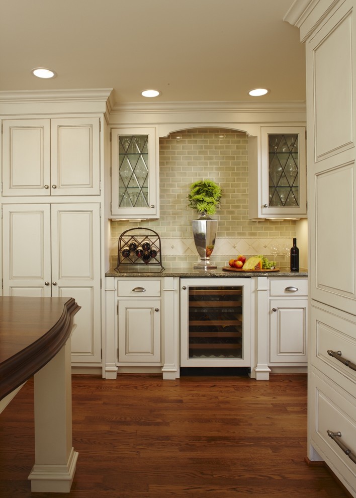 Inspiration for a large timeless l-shaped medium tone wood floor and brown floor eat-in kitchen remodel in Detroit with a farmhouse sink, beaded inset cabinets, white cabinets, granite countertops, green backsplash, subway tile backsplash, paneled appliances, an island and brown countertops