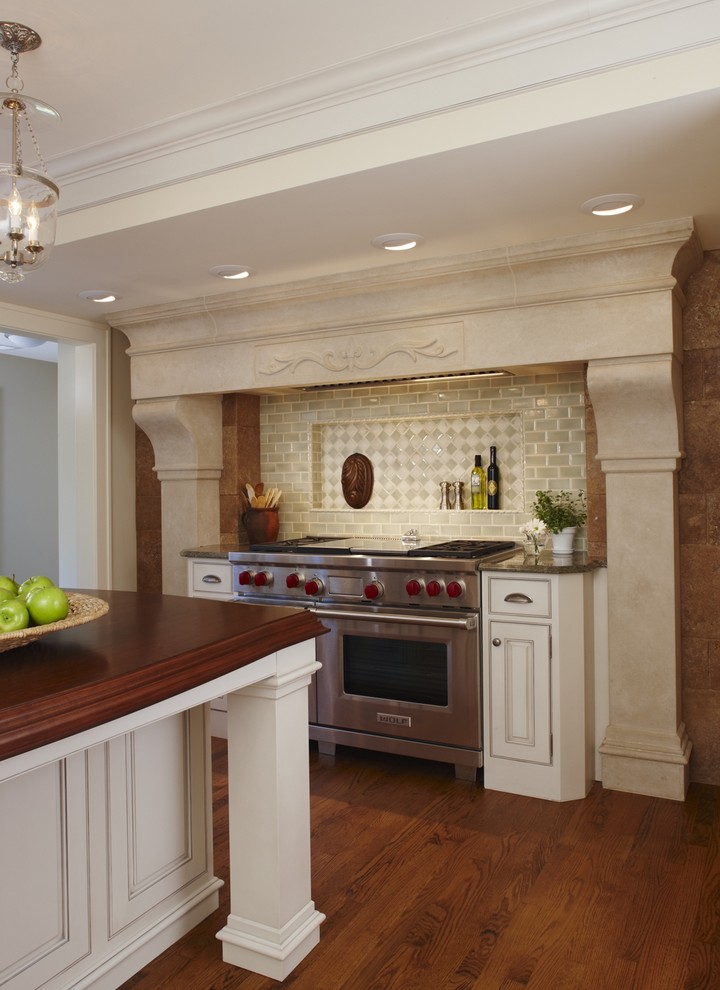 Exempel på ett stort klassiskt brun brunt kök, med en rustik diskho, luckor med profilerade fronter, vita skåp, granitbänkskiva, grönt stänkskydd, stänkskydd i tunnelbanekakel, integrerade vitvaror, mellanmörkt trägolv, en köksö och brunt golv