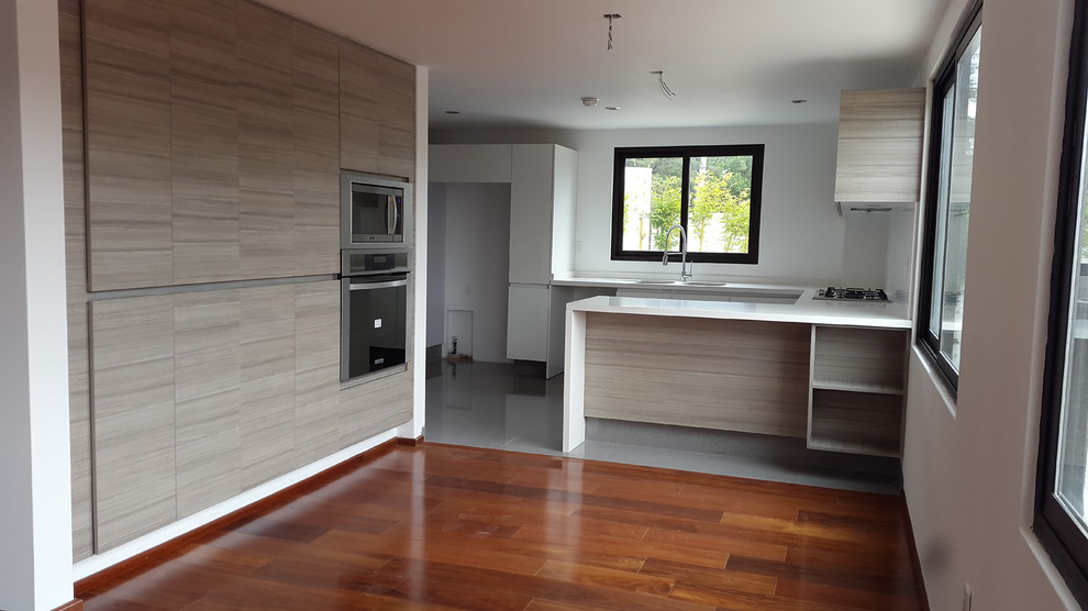 Open concept kitchen - mid-sized contemporary u-shaped porcelain tile open concept kitchen idea in Mexico City with a double-bowl sink, flat-panel cabinets, light wood cabinets, quartz countertops, white backsplash, stainless steel appliances and a peninsula
