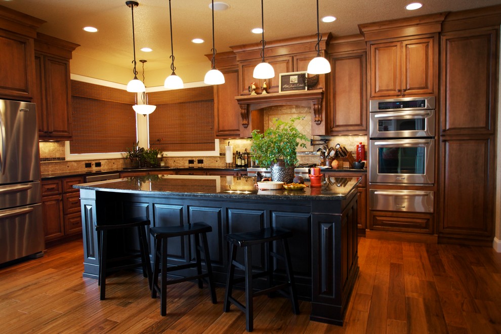 Klassische Küche in L-Form mit profilierten Schrankfronten, hellbraunen Holzschränken, Küchenrückwand in Beige und Küchengeräten aus Edelstahl in Sonstige