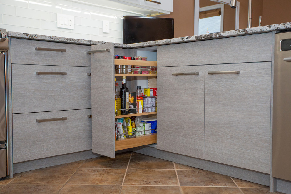 Modern inredning av ett mellanstort kök, med en undermonterad diskho, släta luckor, vita skåp, granitbänkskiva, grått stänkskydd, stänkskydd i glaskakel, rostfria vitvaror, klinkergolv i porslin och en halv köksö