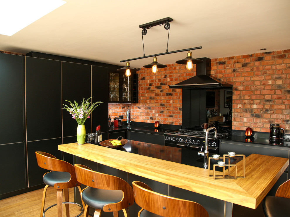Foto di una grande cucina minimal con lavello integrato, ante lisce, ante nere, top in quarzite, paraspruzzi nero, paraspruzzi con lastra di vetro, elettrodomestici neri, pavimento in bambù e top nero