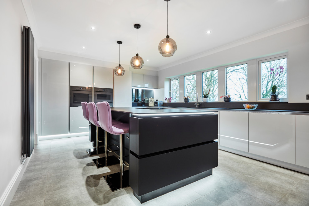 Medium sized contemporary l-shaped kitchen/diner in Other with a built-in sink, flat-panel cabinets, black cabinets, engineered stone countertops, metallic splashback, mirror splashback, coloured appliances, laminate floors, an island, grey floors, black worktops and a coffered ceiling.