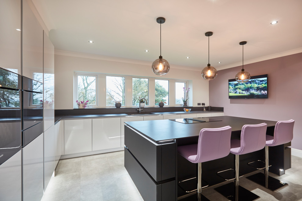 Medium sized contemporary l-shaped kitchen/diner in Other with a submerged sink, flat-panel cabinets, white cabinets, black appliances, an island, grey floors, grey worktops, engineered stone countertops, metallic splashback, mirror splashback, porcelain flooring and a coffered ceiling.