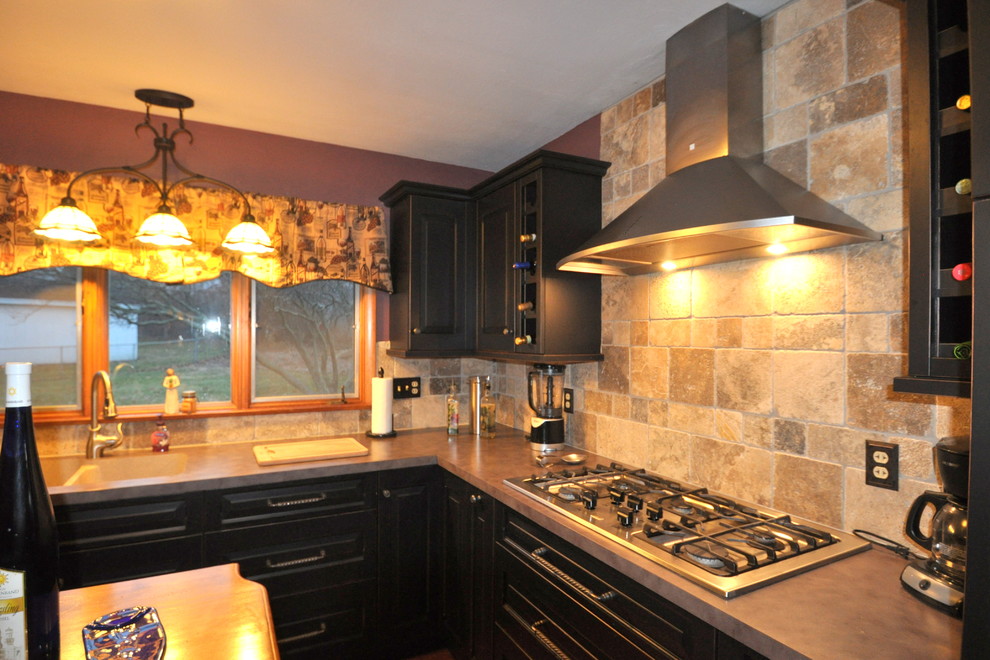 This is an example of a traditional l-shaped kitchen/diner in Chicago with a submerged sink, raised-panel cabinets, black cabinets, laminate countertops, beige splashback, stone tiled splashback and stainless steel appliances.