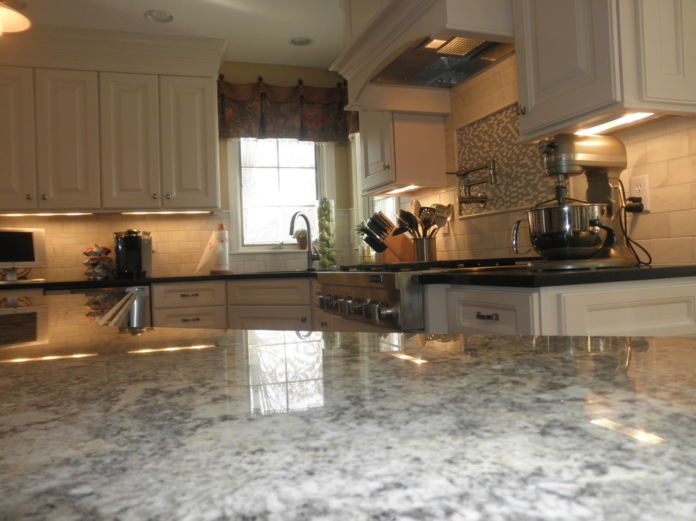 Foto på ett mellanstort funkis kök, med en undermonterad diskho, luckor med upphöjd panel, vita skåp, granitbänkskiva, gult stänkskydd, stänkskydd i stenkakel, rostfria vitvaror, ljust trägolv och en köksö