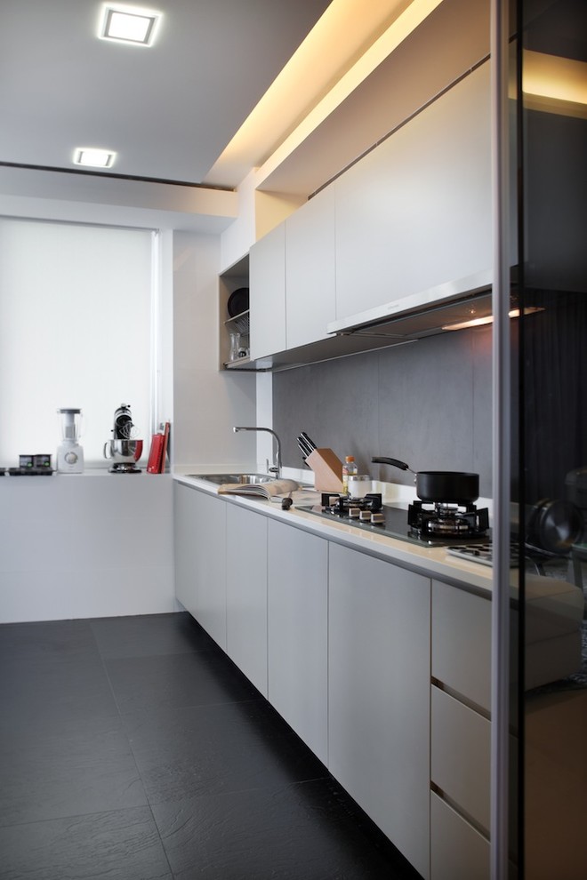 Aménagement d'une cuisine contemporaine avec un évier posé, un placard à porte plane, des portes de placard grises, une crédence grise et un sol noir.