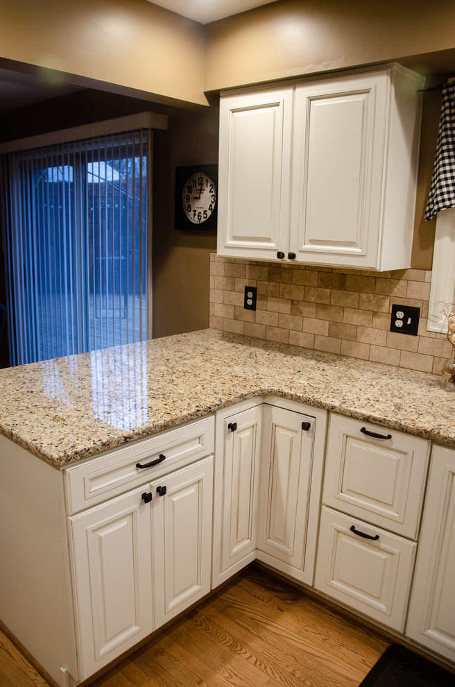 Bild på ett litet lantligt beige beige kök, med en undermonterad diskho, luckor med upphöjd panel, vita skåp, granitbänkskiva, beige stänkskydd, stänkskydd i porslinskakel, rostfria vitvaror, mellanmörkt trägolv och brunt golv