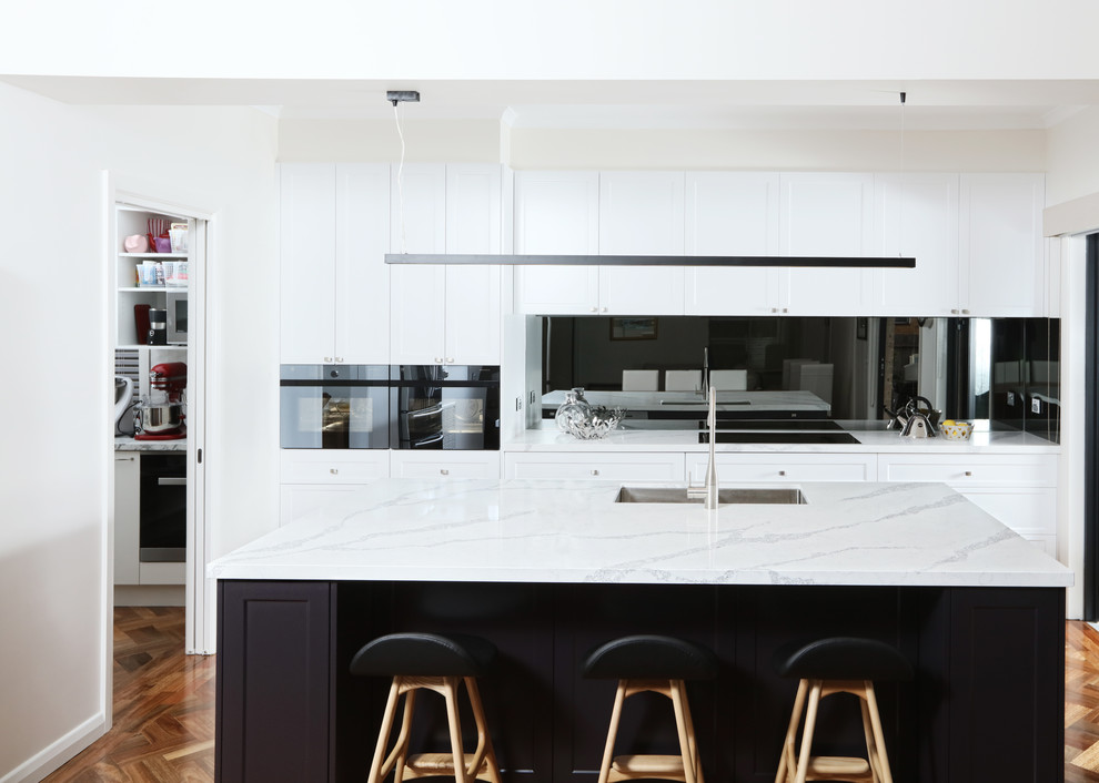 Open concept kitchen - mid-sized transitional galley dark wood floor open concept kitchen idea in Melbourne with an undermount sink, shaker cabinets, quartz countertops, mirror backsplash, black appliances and an island