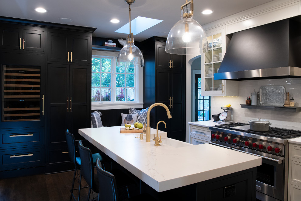 Design ideas for a medium sized classic u-shaped enclosed kitchen in DC Metro with a belfast sink, shaker cabinets, black cabinets, engineered stone countertops, white splashback, cement tile splashback, integrated appliances, dark hardwood flooring, an island, brown floors and white worktops.