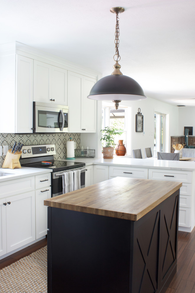 Bild på ett litet vintage vit vitt kök, med en dubbel diskho, skåp i shakerstil, vita skåp, granitbänkskiva, flerfärgad stänkskydd, stänkskydd i keramik, svarta vitvaror, laminatgolv, en köksö och brunt golv