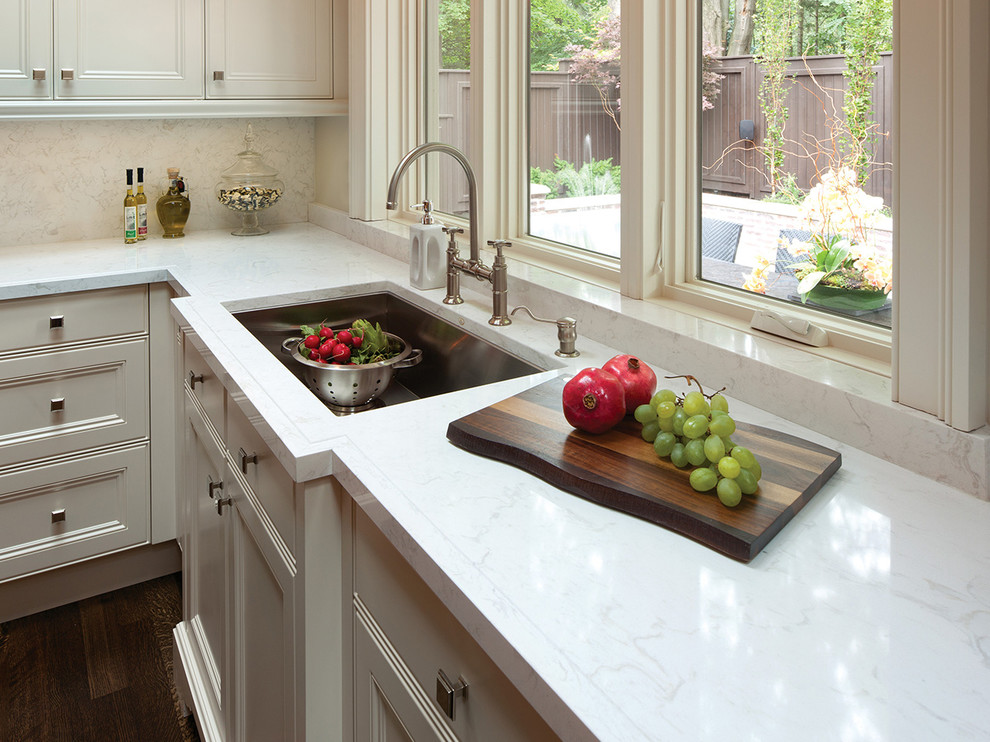 Inspiration for a large transitional medium tone wood floor kitchen remodel in Other with an undermount sink, recessed-panel cabinets, beige cabinets, marble countertops, white backsplash and stone slab backsplash